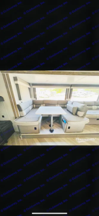 Inviting RV dinette: U-shaped grey seating, white table, large windows. Ideal for comfortable rv rental adventures.. Forest River Wildwood X-Lite 2022