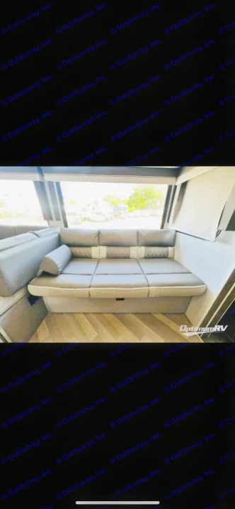 Comfortable L-shaped seating inside an RV rental, featuring modern gray cushions and diamond accents, with a view outside.. Forest River Wildwood X-Lite 2022