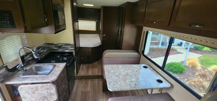 Explore this **rv rental** interior: a well-equipped kitchen, comfortable dining booth, and rear sleeping area for your travels.. Thor Motor Coach Ford E350 2018