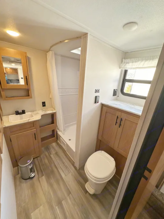 This RV rental features a modern and functional bathroom with a shower, toilet, sink, mirror, and cabinet storage.. Fmc Primetime 2022