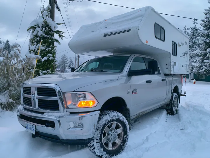 Snow-covered Ram 3500 truck with RV camper for rental, parked amidst snow on a winter day.. Dodge RAM 3500HD 2010