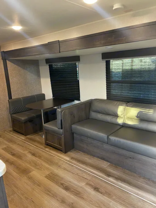 Modern RV rental interior with a cozy dinette booth, sofa, and durable wood-look flooring.. Starcraft Autumn Ridge 2021