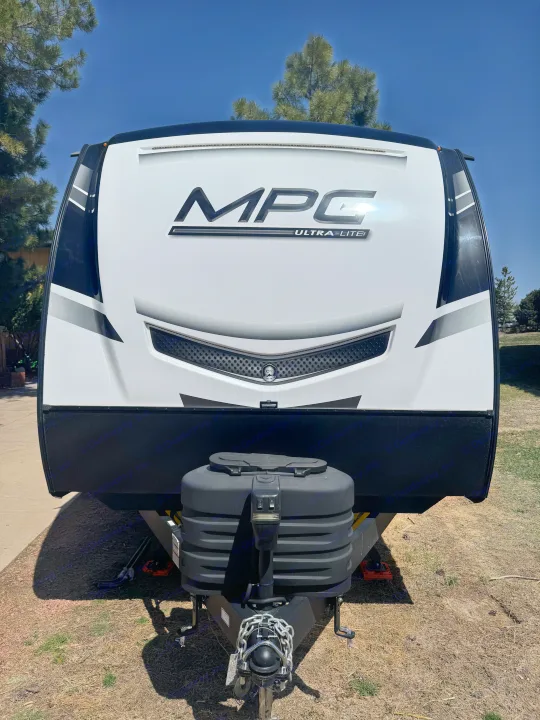 Front view of a white & black MPG Ultra-Lite travel trailer, ideal for an RV rental. Shows hitch, tanks, and clear sky.. Cruiser RV MPG 2500BH 2024