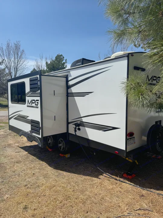Sunny day setup for this white MPG Ultra-Lite RV rental, a travel trailer with extended slide-out, ready for camping.. Cruiser RV MPG 2500BH 2024