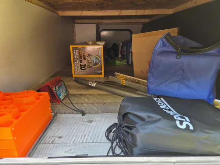 RV rental storage organized with camping essentials: sewer hose, leveling blocks, wheel chocks, and utility bags.. Keystone RV Springdale 2023