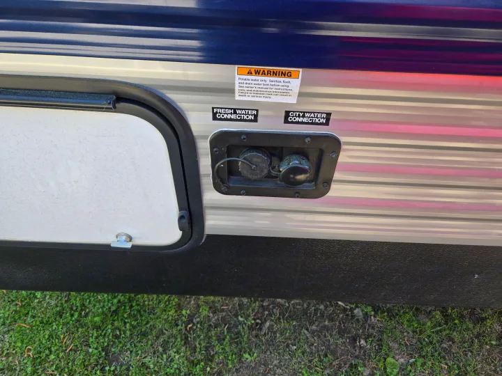 This RV rental's exterior features fresh & city water connections with a warning about sanitizing the potable water tank for safe use.. Keystone RV Springdale 2023