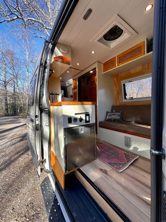 Step into this cozy RV rental with a bright interior, complete with a kitchenette, seating area, and wooden accents.. Mercedes-Benz Sprinter 2022