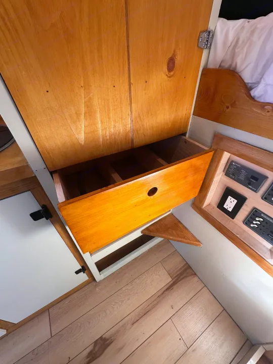 Inside an RV rental: a neat wooden cabinet with an open storage drawer and an integrated electrical control panel.. Mercedes-Benz Sprinter 2022
