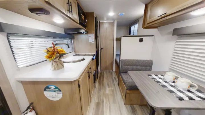 Inside this bright RV rental: full kitchen with sink, cozy dinette, and bunk beds. Your next road trip adventure awaits!. Forest River 17' Bunkhouse 2025