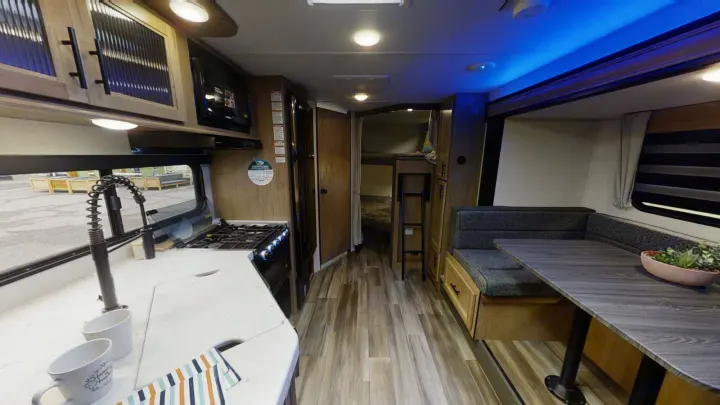 Modern RV rental interior: kitchen, dinette, bunks, and blue accent lighting, ideal for family travel.. Forest River 26' Bunkhouse with Slide 2025