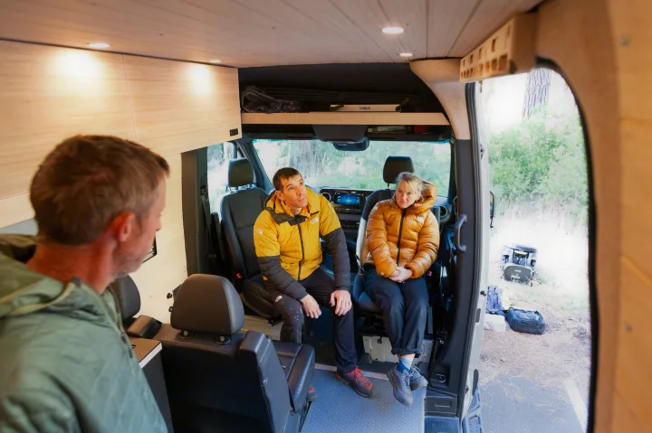 Two passengers in an RV rental van, dressed for outdoor adventure, are seated in the versatile interior.. Mercedes-Benz Sprinter 2024