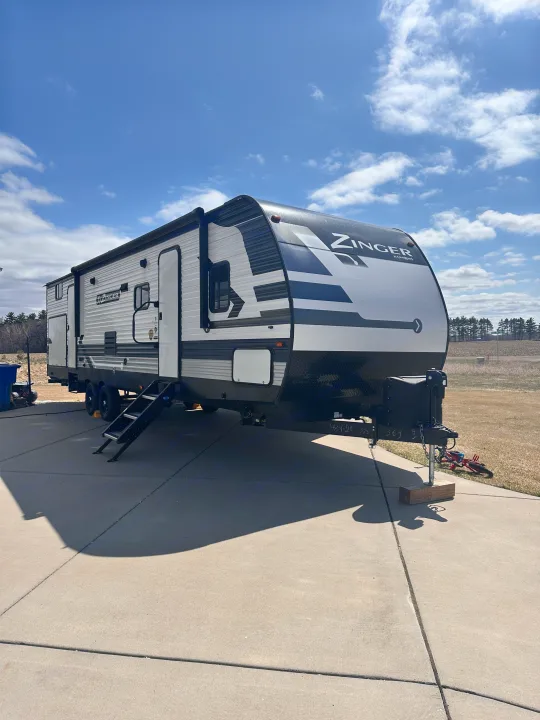 A Zinger travel trailer, perfect for an RV rental, parked on a sunny concrete driveway with blue skies.. Crossroads RV Zinger 2020