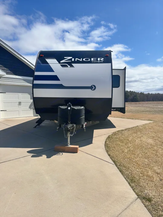 A spacious Zinger RV rental is parked on a driveway, ready for adventure, with its slide-out extended.. Crossroads RV Zinger 2020