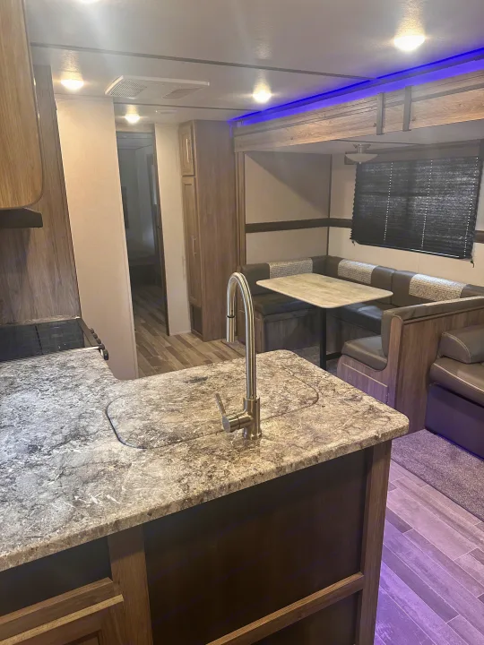 Explore this RV rental's spacious interior, featuring a modern kitchen island with a sink and a comfortable dinette area.. Crossroads RV Zinger 2020