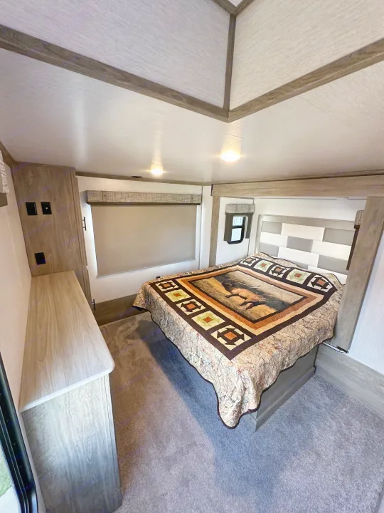 Discover comfort in this RV rental bedroom: cozy bed with elk quilt, modern headboard, and ample storage.. Forest River Salem Hemisphere 2022