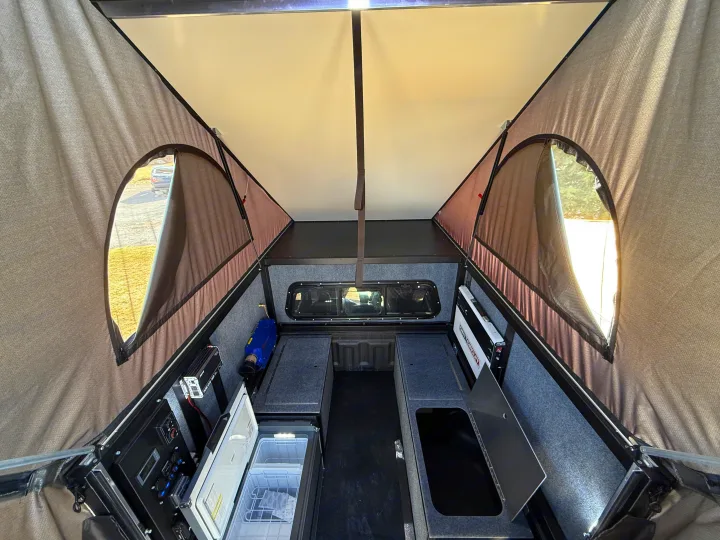 Inside a truck camper, ideal for RV rental, with a fridge, power panel, and pop-up tent for camping comfort.. Ford Ranger 2300 Cc 2022