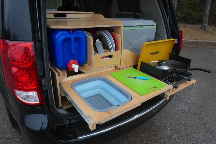An RV rental's clever tailgate kitchen for camping: pull-out sink, stove, organized storage, and water. Perfect for van life.. Dodge Grand Caravan 2014