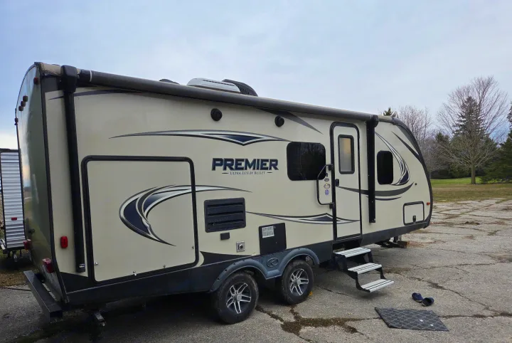 A light-colored travel trailer with an awning and steps, ready for an rv rental camping adventure.. Keystone RV Bullet Premier Ultra 2018