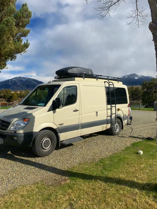 Cream Mercedes Sprinter RV rental parked in a scenic mountain setting with trees.. Sportsmobile Regular Body 2013