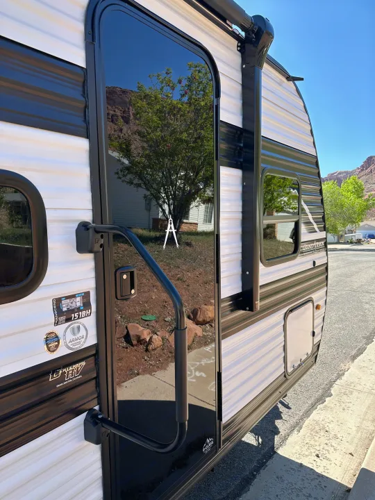 Modern RV rental, a travel trailer with reflective door showing trees and distant mountains.. Transcend One 2025 2025