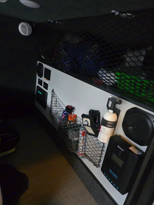 Explore a modern RV rental interior with organized cargo nets, control panel, Renogy solar charge controller, fire extinguisher, and detector.. InTech RV InTech RV Trailer 2021