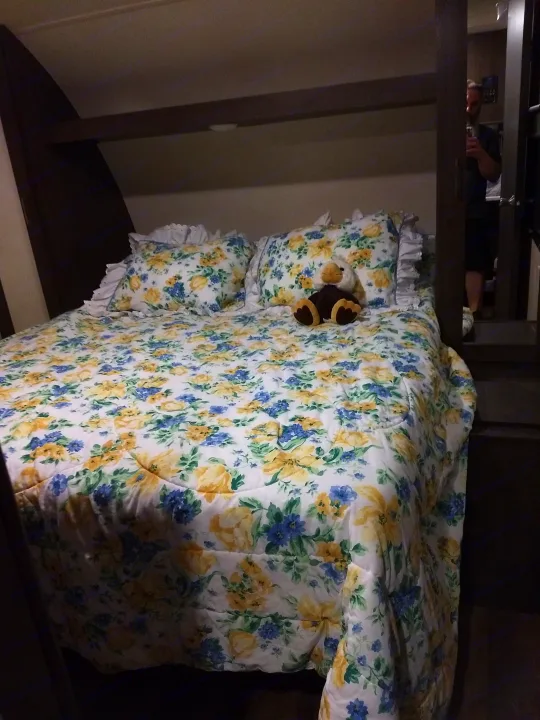 Relax in this RV rental's cozy bedroom. Features floral bedding with yellow & blue flowers, and a cute plush toy.. Forest River Salem 2018
