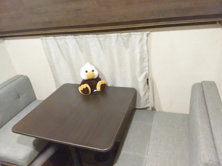 Cozy RV rental dinette featuring a plush eagle toy on the table, with comfortable grey benches and curtains for travel.. Forest River Salem 2018