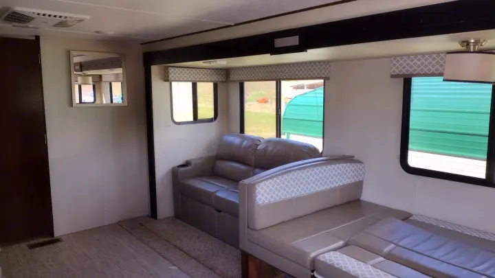RV rental interior featuring a modern living space with comfortable sofa, dinette, and bright windows.. Avenger ATI 2019