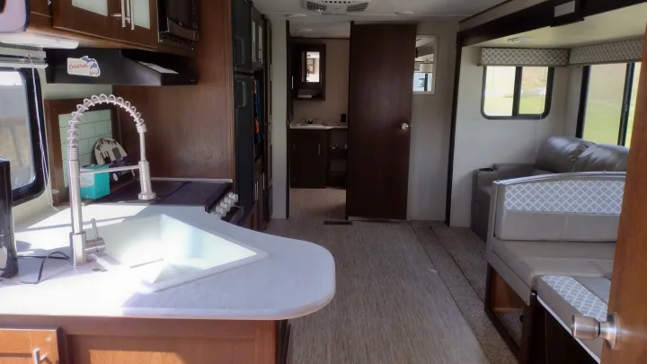 Spacious rv rental interior showcasing a modern kitchen, comfortable living area, and bathroom access. Ideal for travel.. Avenger ATI 2019