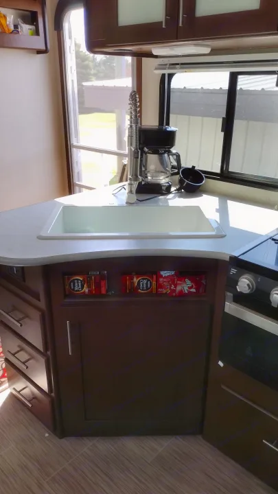 Compact RV rental kitchen featuring a modern sink, coffee maker, stove, and convenient under-counter storage.. Avenger ATI 2019