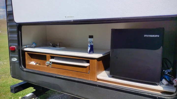 RV rental outdoor kitchen with sink, mini-fridge, and storage. Perfect for camping adventures.. Avenger ATI 2019