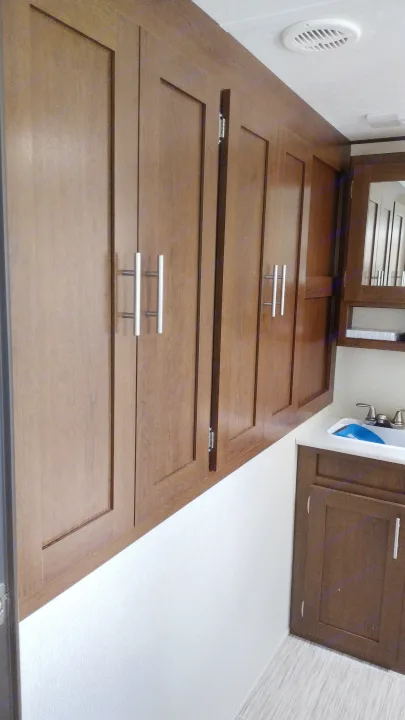Modern RV rental interior with dark wood overhead storage cabinets, sleek silver handles, and a compact sink area. Efficient use of space.. Avenger ATI 2019