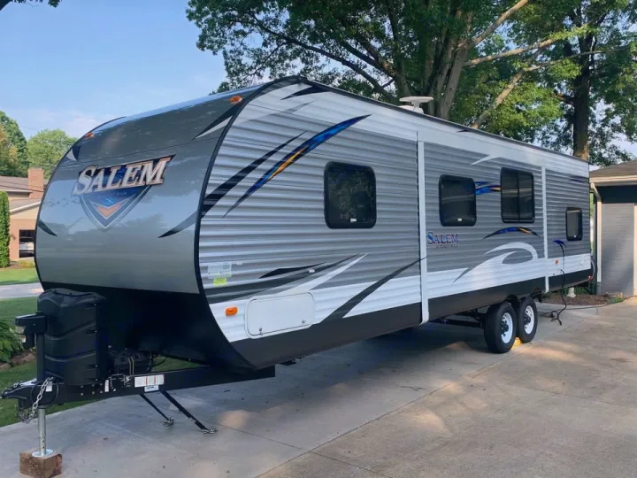 A grey & white Salem travel trailer, ideal for an rv rental adventure. Features: front hitch, multiple windows & dual axles.. Forest River Salem 2018