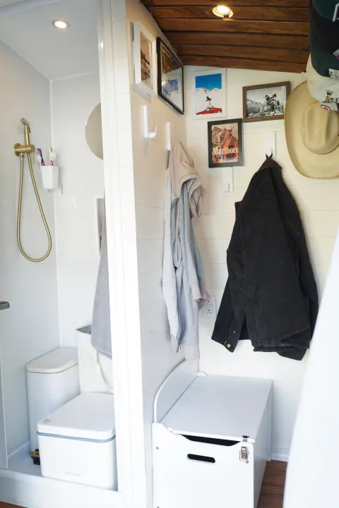 Cozy RV rental interior: gold shower, Trelino toilet, white shiplap walls with art, hooks for jackets & hats.. Ford Transit Custom 2022