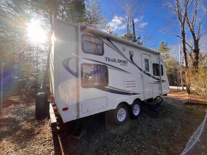 White "Trail Sport R-Vision" RV rental parked in a sunny wooded campground. Great for outdoor adventures.. R-Vision Trail Sport 2014