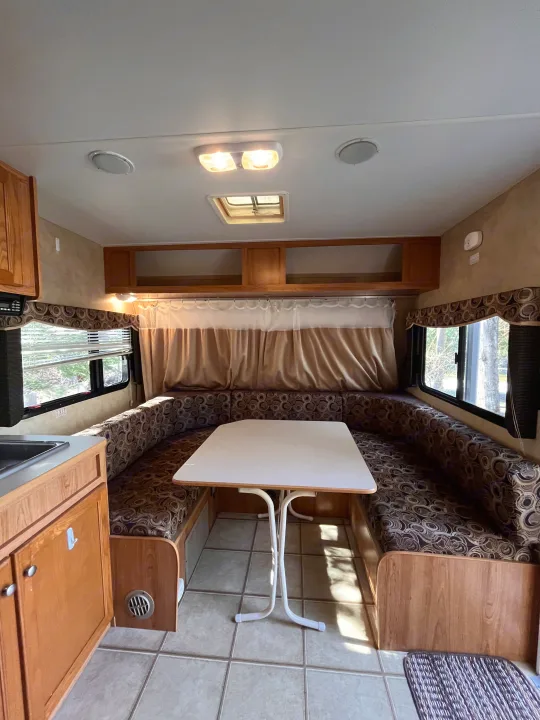 RV rental interior: U-shaped dinette, kitchen, overhead storage, and sunlit windows.. R-Vision Trail Sport 2014