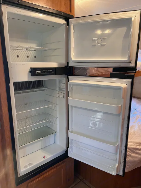 Open RV rental refrigerator and freezer interior, clean and empty, ready for your trip.. R-Vision Trail Sport 2014