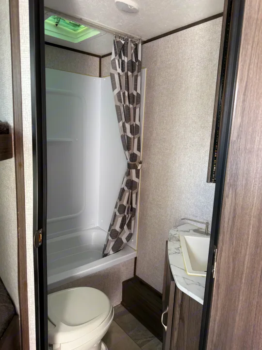 Compact RV rental bathroom with shower, toilet, and sink, perfect for on-the-go comfort.. Dutchmen Kodiak Ultra Lite 2021