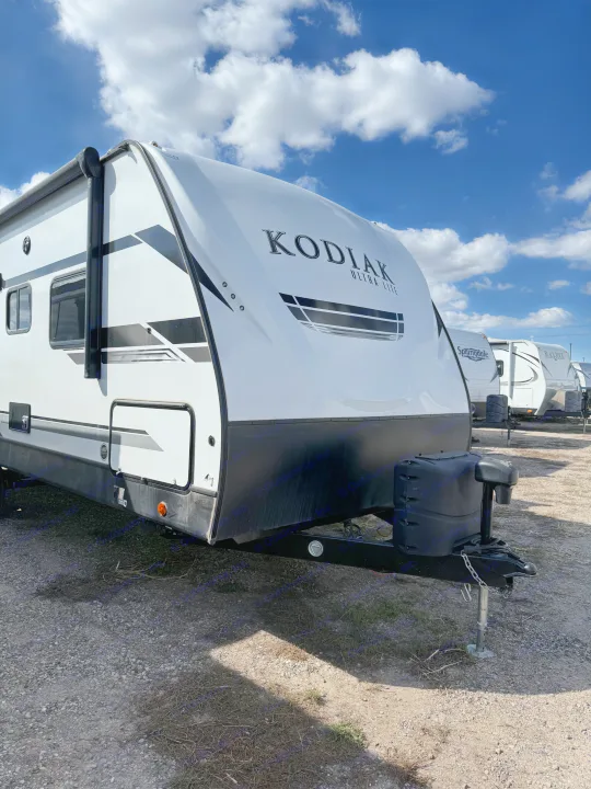 This Kodiak Ultra Lite travel trailer is ready for your next RV rental adventure, parked on a sunny gravel lot.. Dutchmen Kodiak Ultra Lite 2021