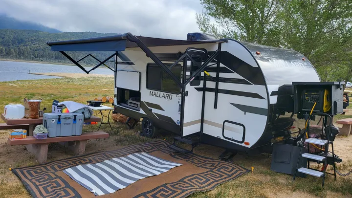 Lakeside rv rental setup: Mallard travel trailer with awning, generator, picnic area, and scenic mountain views.. Heartland RVs Mallard 2021