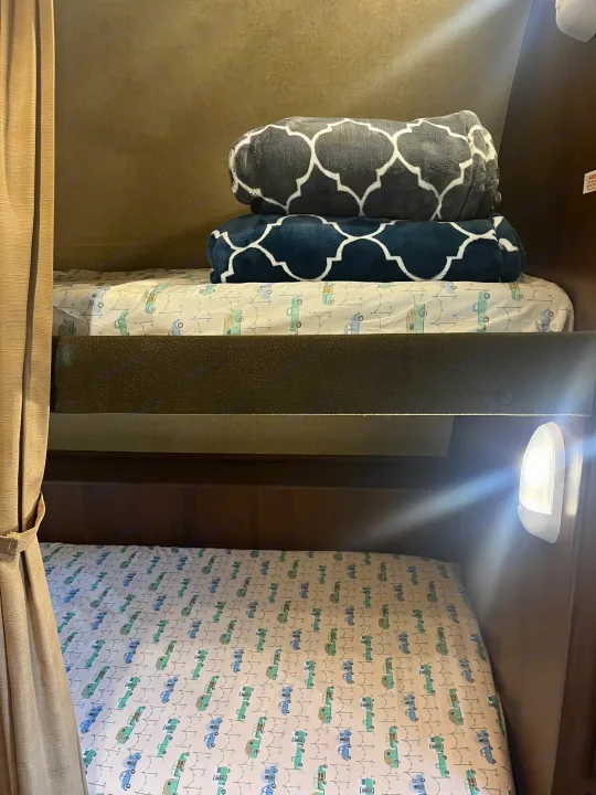 Comfortable bunk beds with truck sheets and blankets in an RV rental, featuring a reading light.. Jayco Jay Feather Ultra Lite 2014