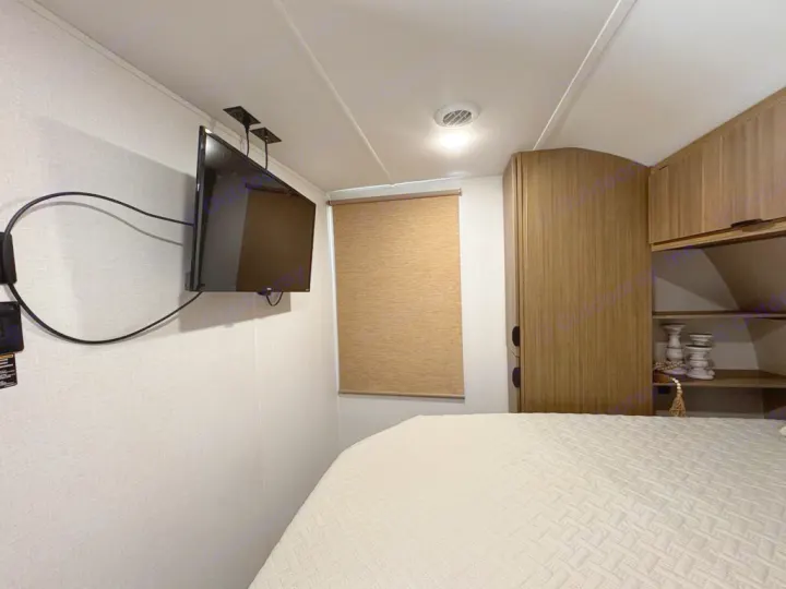RV rental bedroom interior: shows a cozy bed, wall-mounted TV, window with shade, and wooden cabinets.. Forest River Salem 31kqbts 2025