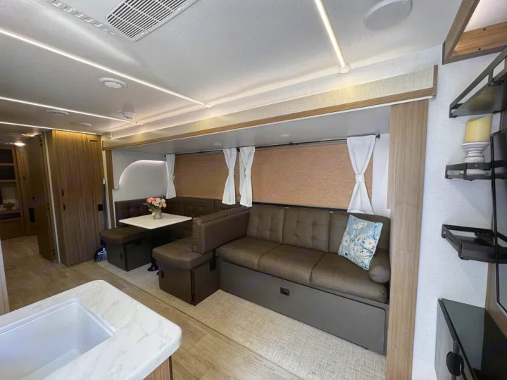 Spacious RV rental interior with a comfortable dinette, sofa, and kitchen counter. Bright, modern living space.. Forest River Salem 31kqbts 2025