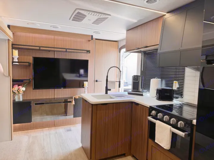 Step inside this modern RV rental! View of the spacious kitchen with appliances and living area with TV.. Forest River Salem 31kqbts 2025