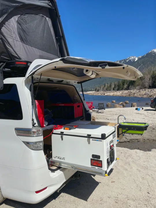White minivan RV rental, equipped with rooftop tent, pull-out fridge, and outdoor sink, ideal for lake & mountain adventures.. Toyota Dreamseeker Voyager 2008