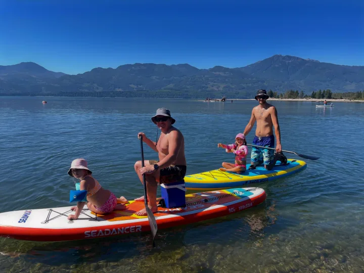 Family paddleboarding fun at a scenic lake, perfect for an RV rental adventure in nature.. Toyota Dreamseeker Voyager 2008