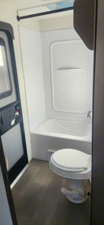 RV rental: Compact bathroom featuring a white toilet, integrated bathtub, and shower. Ideal for travel comfort.. Cruiser RV Avenir 2024