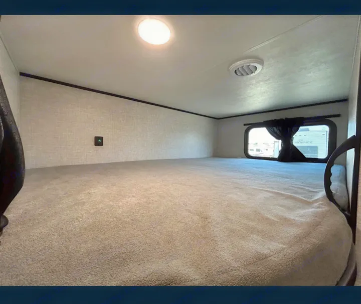 Cozy RV rental sleeping area with a comfortable carpeted bunk, window, and overhead light.. Jayco 267BHS 2025