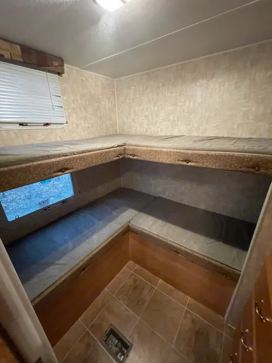 Cozy RV rental bunk bed area with a U-shaped lower berth, window, and tiled floor, ready for your next adventure.. Forest River Cherokee 2008