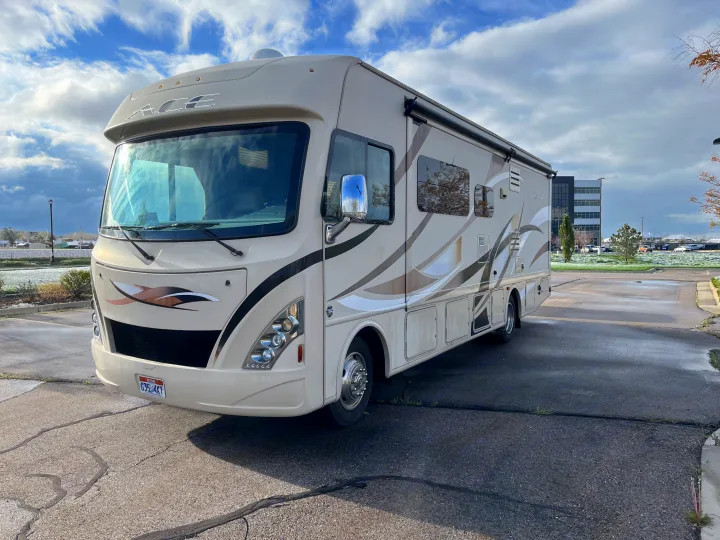 Beige ACE Class A RV rental, parked on asphalt. Ready for your next travel and camping adventure.. Thor A.C.E. 2016
